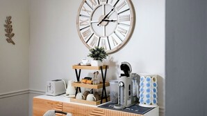 Eine Küche mit einem Holzkorpus, einem weißen Toaster, einer Kaffeemaschine und einer Uhr an der Wand.