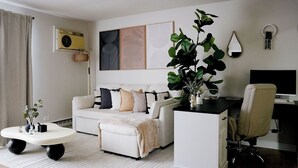 Un salon moderne avec un canapé, une table basse, un bureau et une grande plante.