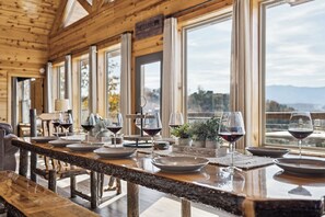 A wooden cabin interior with a dining table set for a meal, large windows, and a view of the mountains. - Private Heated Pool -VIEWS - Lux Cabin -Game/Movie Room -Hot Tub -Pet friendly (Sevierville)