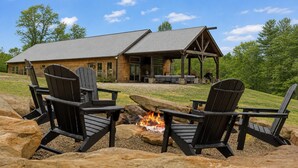 Una cabaña con un brasero y sillas Adirondack al frente.
