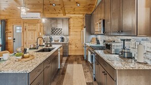 Una cocina moderna con armarios de madera, encimeras de granito y electrodomésticos de acero inoxidable.