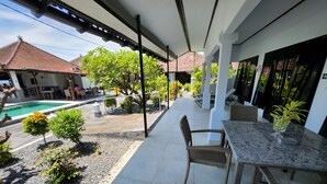 A covered outdoor area with a pool, seating, and potted plants. - Bugbug Beach Resort (Karangasem)