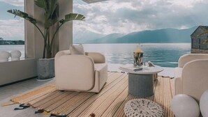 A modern room with a large window overlooking a lake and mountains. There is a sofa, a coffee table, and a potted plant. - Mandi Lake View Inn (Dali)