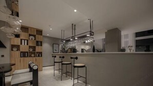 A modern kitchen with a bar area, wooden cabinets, and bar stools. - Mandi Lake View Inn (Dali)