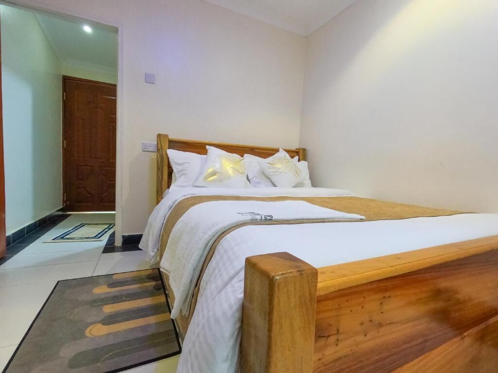 A bedroom with a wooden bed, white bedding, and a small rug on the floor.