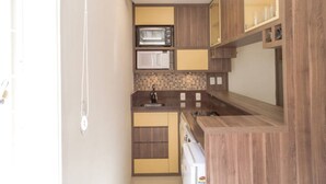 Eine kleine Küche mit Holzschränken, einer Mikrowelle und einem Spülbecken.