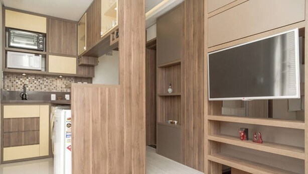 Eine moderne Küche mit integrierten Geräten, Holzschränken und einem Flachbildfernseher.