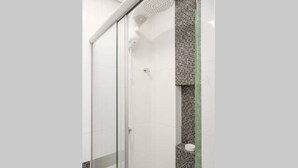 Eine moderne Dusche mit Glastür, gefliesten Wänden und einer vertikalen, grünen Linie.
