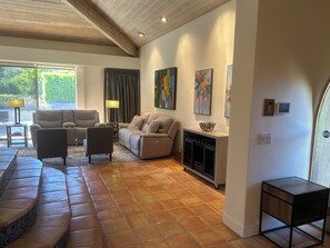 Een ruime woonkamer met een zithoek, een open haard en kunstwerken aan de muur.
