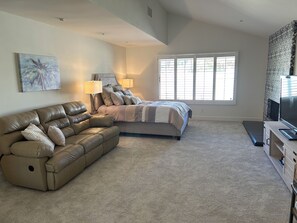 A bedroom with a bed, a sofa, a TV, and a window with blinds. - Corner fairway & mountain view 3 BR+3.5 BA condo, chef's kitchen, private spa! (Rancho Mirage)