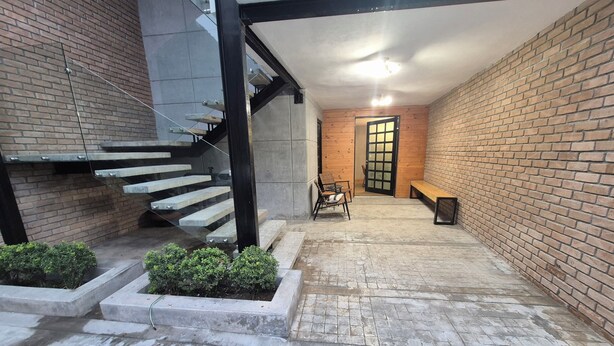 A modern interior with a staircase, seating area, and a door leading to another room.