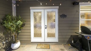 A house entrance with frosted glass doors, a potted plant, a barbecue grill, and string lights. - 4BR Dream Family Stay! ☆ King Bed / Home Theatre / Large Backyard ☆ Pet Friendly (Sturgeon County)