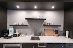 Une cuisine moderne équipée d’un lave-vaisselle encastré, d’une machine à café et d’un bloc à couteaux.