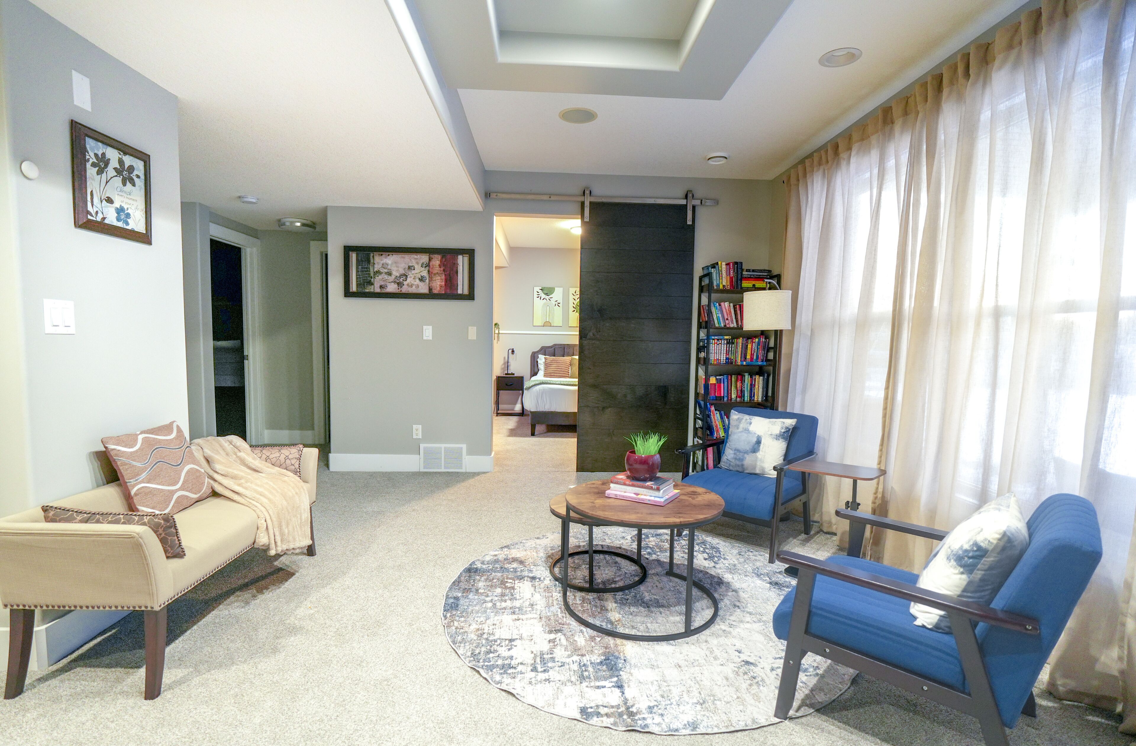 A living room with a sofa, armchair, coffee table, and bookshelf.