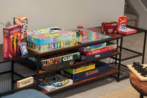 A shelf with various board games including Codenames, Jenga, and Monopoly. - Dream Family stay w/ King Bed and Home Theatre! Large Backyard & Pet Friendly (Sturgeon County)
