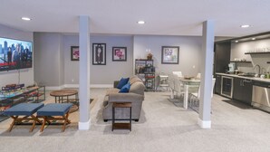 Una sala de estar moderna con un televisor de pantalla plana, un sofá, una mesa de centro y un comedor con una cocina al fondo.