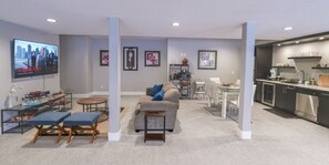 Un salon moderne doté d’un téléviseur à écran plat, d’un canapé, d’une table basse et d’un coin repas avec une cuisine en arrière-plan.