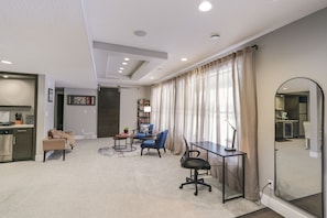 Ein modernes Wohnzimmer mit einer Couch, Sesseln, einem Couchtisch und einem Essbereich mit Tisch und Stühlen.