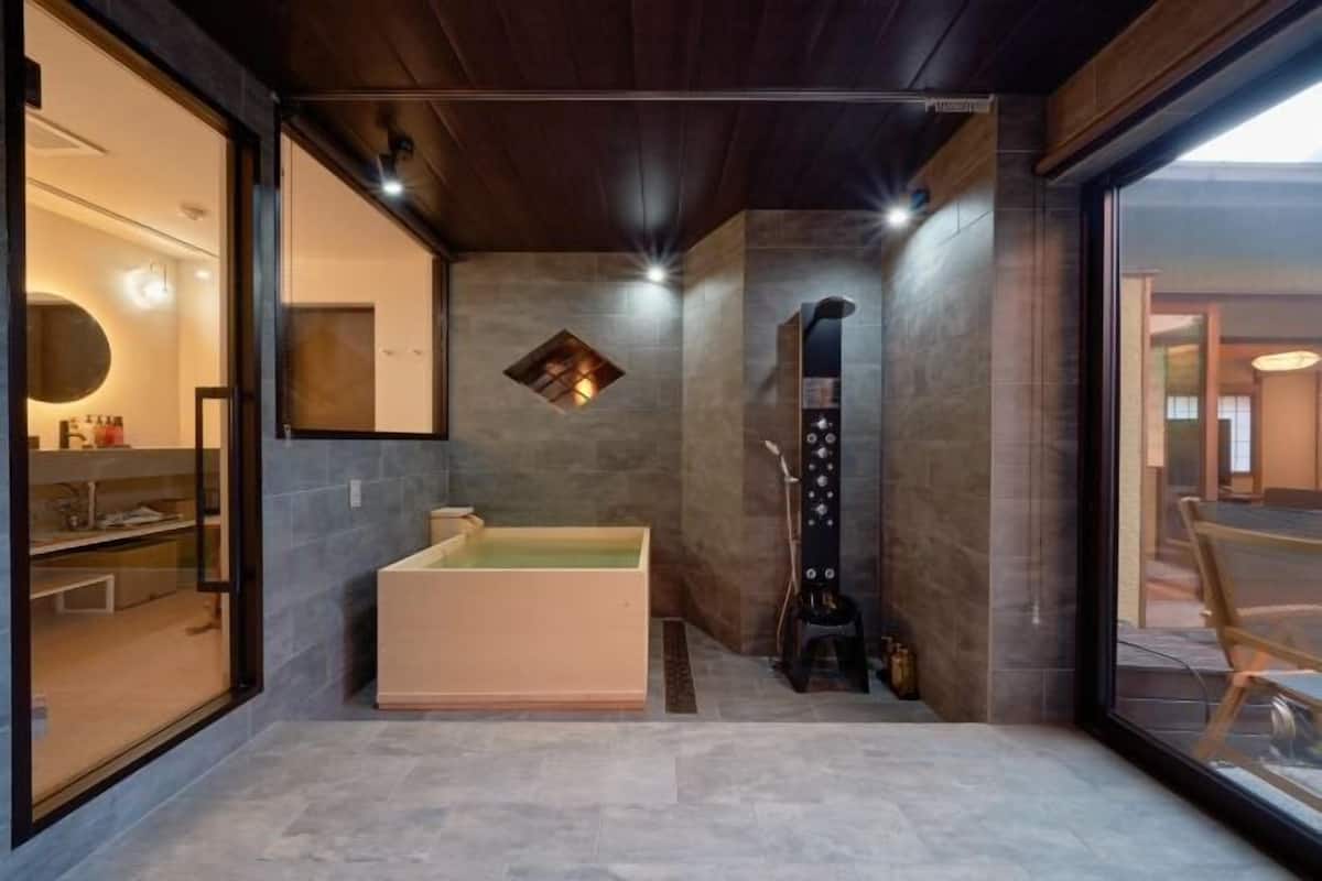 Une salle de bain moderne dotée d’une baignoire, d’une douche et d’un espace coiffeuse délimité par des parois en verre.