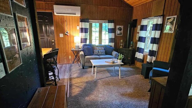 L’intérieur d’un chalet accueillant, avec un plafond en bois, un canapé agrémenté d’un coussin, une table et un banc.