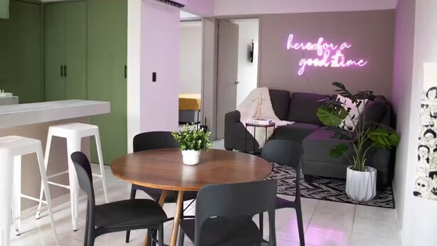 Et moderne opholdsrum med spiseplads, sofa og en neonreklame.