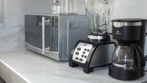 Et køkken med mikrobølgeovn, blender og kaffemaskine.