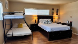 A bedroom with a bunk bed, a single bed, wooden flooring, two bedside tables with lamps, and a wall clock. - Spacious 5-bedroom house in terrific San Diego with AC (San Diego)