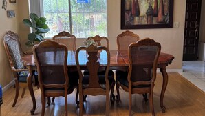 A dining area with a wooden table and chairs, a ceiling fan, and a window with a view of greenery. - Spacious 5-bedroom house in terrific San Diego with AC (San Diego)