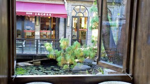 A view through a window of a restaurant with a pond and potted plants. - Dali Ancient City Ped Mall Meishu B & B (Dali)