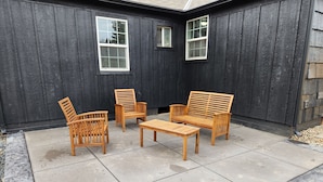 A patio with wooden furniture against a dark wooden wall. - Cute Parkside House (Grants Pass)