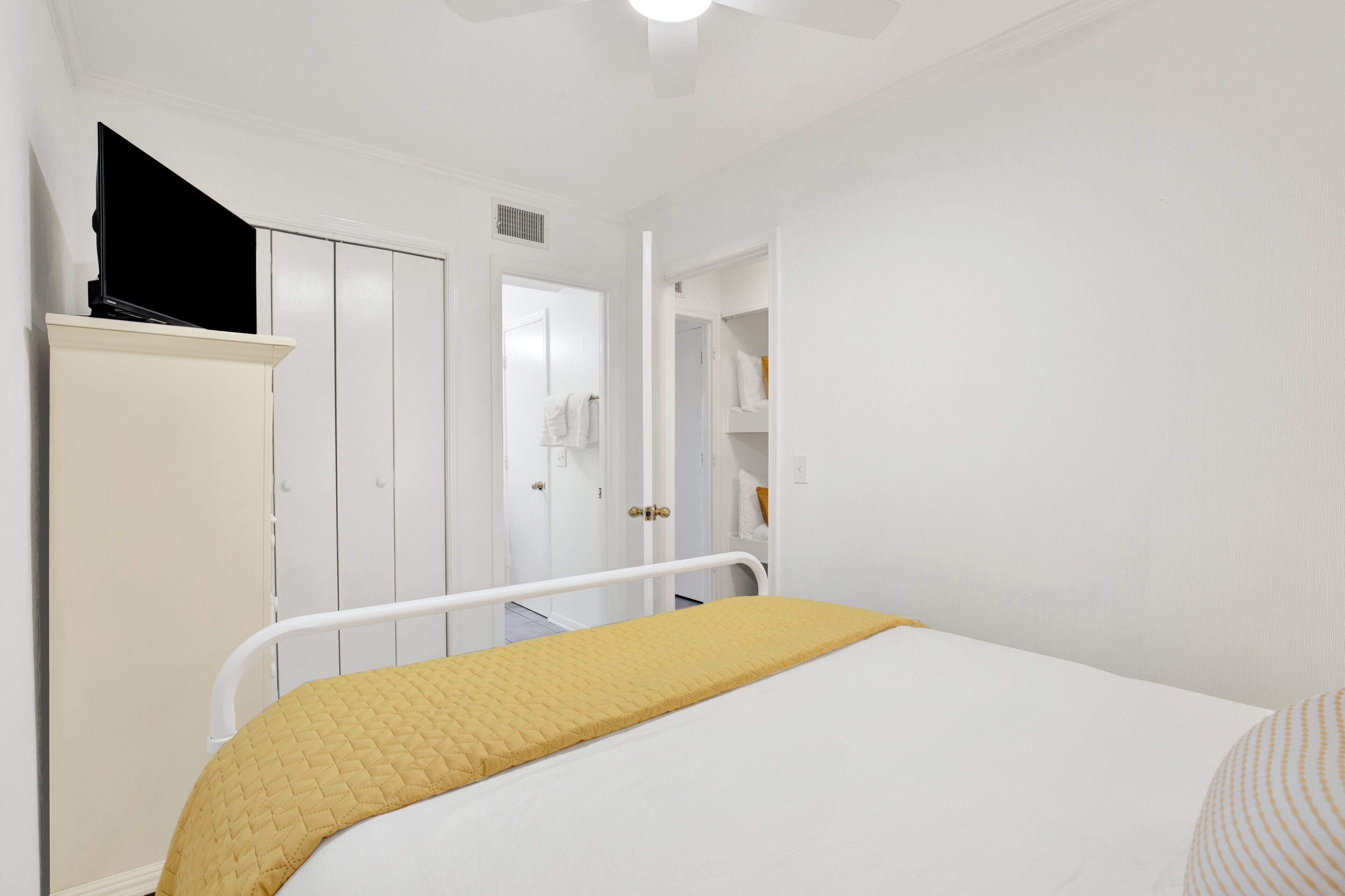 A bedroom with a bed, a white wardrobe, and a door leading to a bathroom.