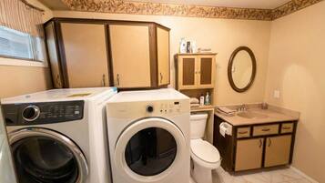 A compact bathroom with a washing machine, a toilet, and a sink.