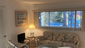 A living room with a sofa, two armchairs, a TV, a lamp, and a window with bars. - Exceptional Dewey Beach Stay Central Location Near Ocean & Bay (Dewey Beach)