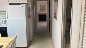 A narrow hallway with a kitchen area on the left, a dining table with chairs, and a door leading to another room on the right. - Exceptional Dewey Beach Stay Central Location Near Ocean & Bay (Dewey Beach)