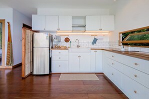 Een koelkast, een kookplaat, kookgerei, borden en bestek