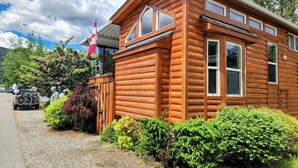 A wooden cabin with a porch, a flag, and a gravel driveway.