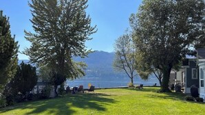 A grassy yard with trees and a lake view.
