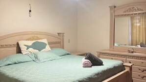 Quarto com cama, penteadeira, espelho, ventilador de teto e luminária.