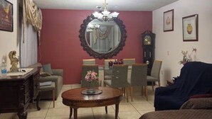 Uma sala de estar com uma mesa redonda, um sofá, um relógio e um candelabro.