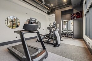 A gym with treadmills, elliptical machines, and weight benches. - Petal & Palm-Rooftop Patio & Gym-Mins to Broadway (Nashville)