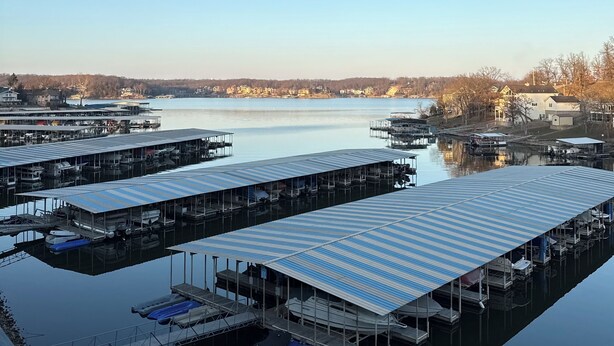 A marina with docked boats and a clear view of the surrounding buildings and landscape. - Welcome to Your Lakefront Retreat (Osage Beach)