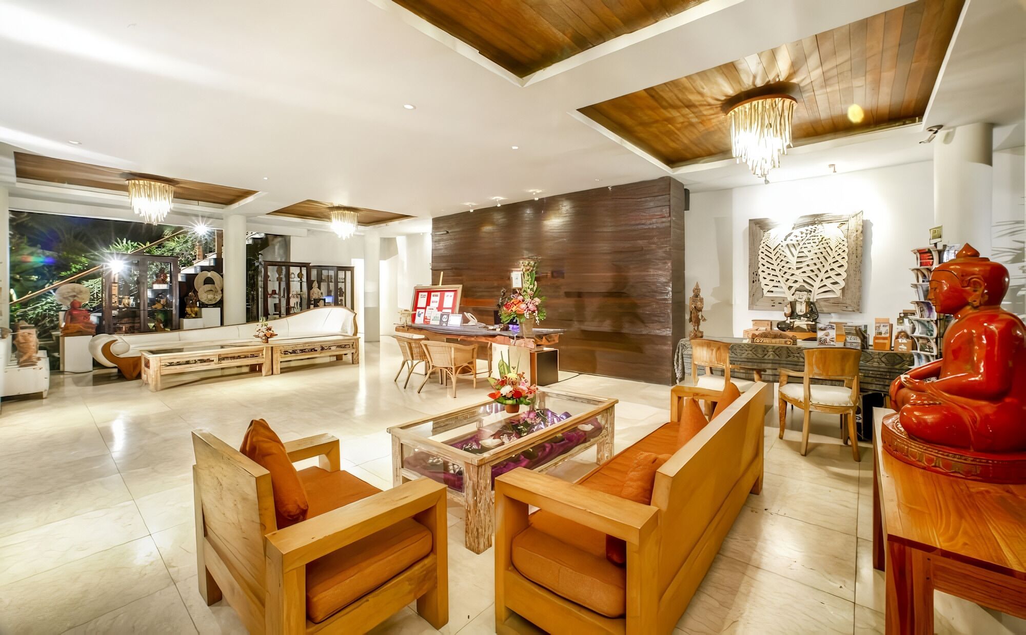 Un salón amplio con un sofá de madera, una mesa de centro y una estatua roja.