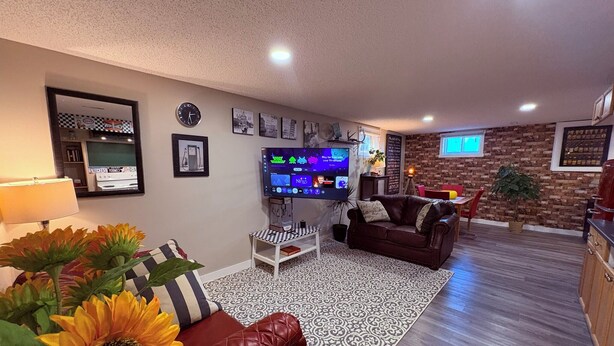 Una sala de estar con televisión, sofá de cuero, alfombra estampada y una mesa de centro.