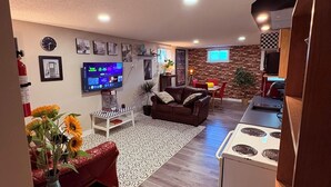 Una sala de estar moderna con un televisor de pantalla plana, un sofá de cuero marrón y un comedor con una cocina al fondo.