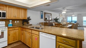 Una cucina moderna con piani in granito, mobili in legno, lavastoviglie e un'ampia finestra con vista.