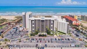 Un hotel con diversi piani, un parcheggio e vista sulla spiaggia e sull'oceano.