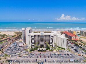 Ein Hotel mit mehreren Etagen, einem Parkplatz und Blick auf Strand und Meer.
