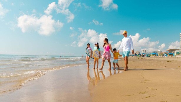 Una spiaggia con persone che camminano lungo la riva.