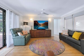 Un saló modern amb un sofà, una taula de centre, una televisió i una catifa decorativa.
