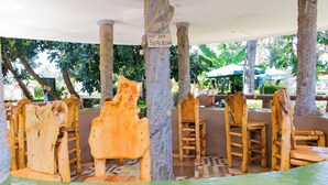 A wooden chair seating area with a 'No Smoking' sign, surrounded by trees and a tiled floor. - Northwood Gardens & Adventure Park (Mukurweini)